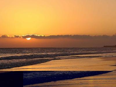 Tramonto sulla spiaggia con faro e mare calmo