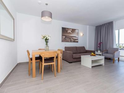 Soggiorno luminoso con tavolo da pranzo, divano, poltrona e balcone con fiori.