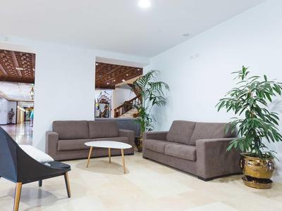 Area lounge moderna dell'hotel con divani, poltrone e piante in ambiente luminoso.