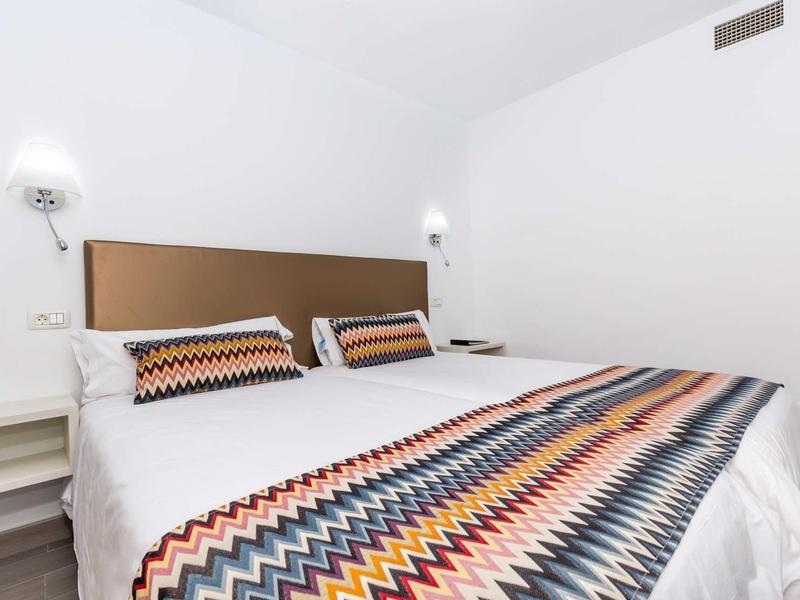 Camera d'hotel moderna con letto matrimoniale e biancheria con motivo a zigzag colorato