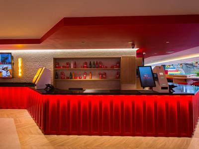 Moderno banco reception rosso in un hotel con layout spazioso e illuminazione luminosa