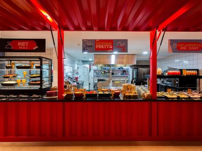 Banco self-service rossa con vari prodotti da forno in una panetteria moderna.