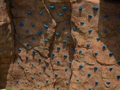Kletterwand mit orangefarbenen Felsen und blauen Griffen in einem Hotel-Freizeitbereich.