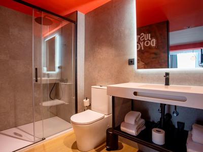 Bagno moderno con doccia walk-in, toilette e lavabo con grandi specchi e luce calda.
