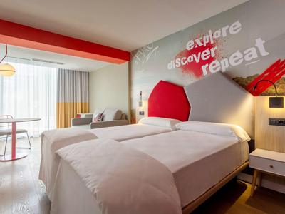 Camera d'albergo moderna con letto grande, scrivania e decorazione murale colorata.