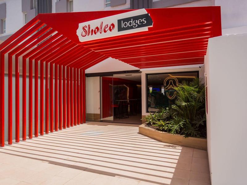 Ingresso rosso con tenda parasole e fioriera in un hotel o resort.