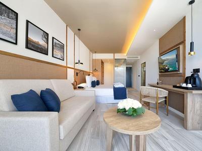 Jasny pokój hotelowy z sofą, podwójnym łóżkiem, biurkiem i nowoczesnym wystrojem.