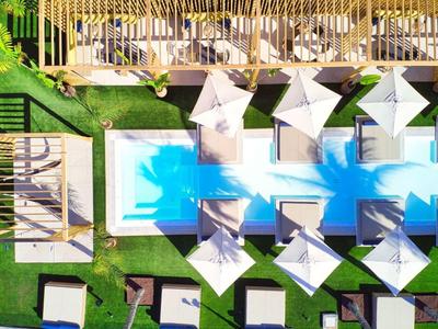 Widok z góry na basen hotelowy z parasolami, leżakami i zielonymi trawnikami.