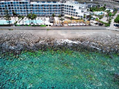 Hotel przy skalistym wybrzeżu z czystą turkusową wodą i palmami