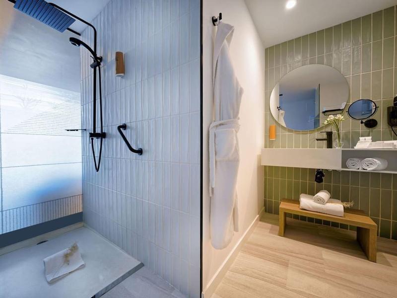 Nowoczesna łazienka hotelowa z prysznicem i umywalką z lustrem i ręcznikami.