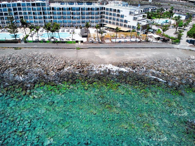 Hotel przy skalistym wybrzeżu z czystą turkusową wodą i palmami