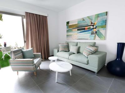 Modern living room with sofa, armchair, coffee table, and view of a terrace.