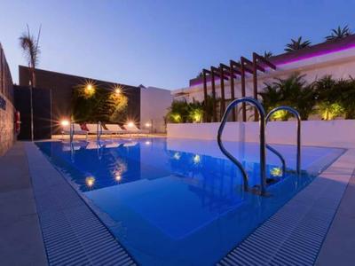 Modern outdoor pool with lounge chairs and atmospheric lighting at dusk.