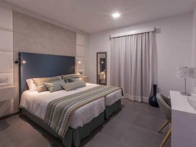 Modern hotel room with double bed, desk, and neutral colors.