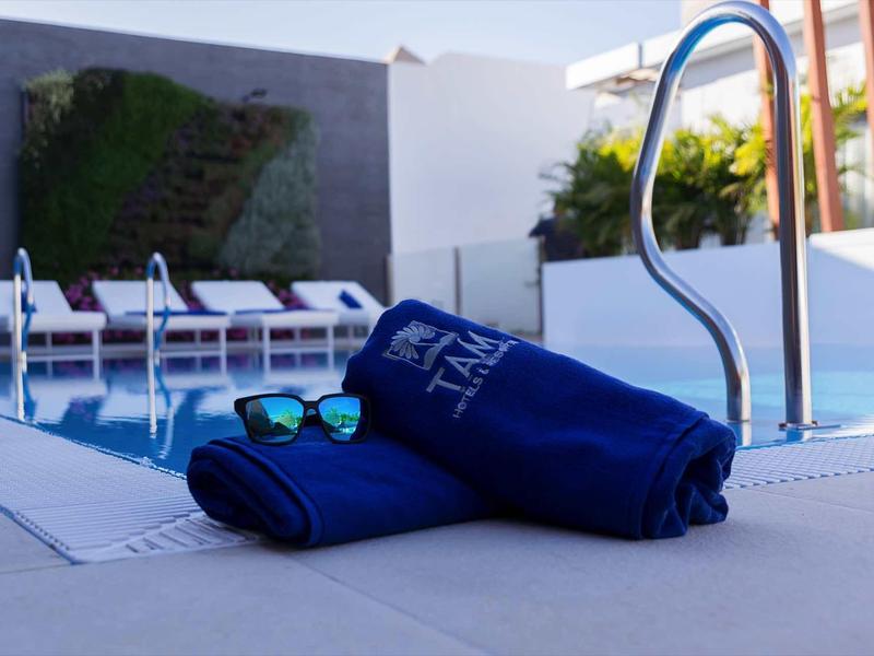 A pool area with two blue towels and sunglasses on the edge of the pool.