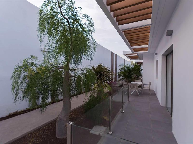 Modern balcony with glass railing, plants, and seating area along white facade.