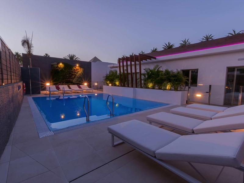 Modern pool area with loungers and ambient lighting at dusk.