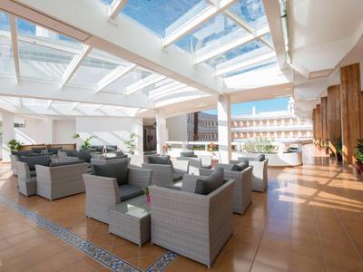 Helle, moderne Dachterrasse mit grauen Sitzmöbeln, Glasüberdachung und Sonnenschein.