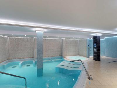 Moderner Innenpool mit klarem Wasser, bequemen Liegen und hellen Wänden, sanfte Beleuchtung.