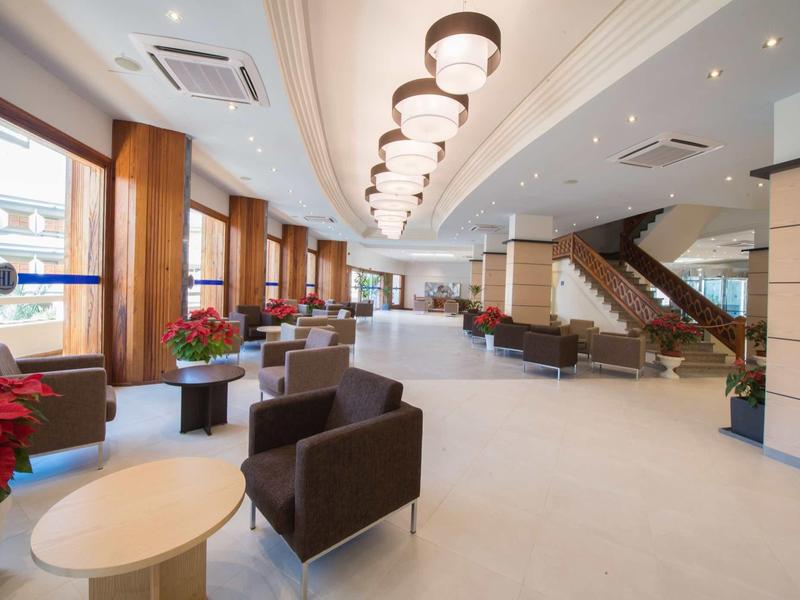 Jasna lobby hotelowa z wygodnymi fotelami, dużymi oknami i nowoczesnym oświetleniem