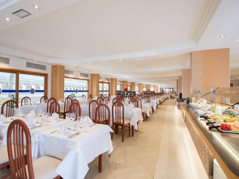 Elegancka restauracja z białymi obrusami, drewnianymi krzesłami i długim bufetem.