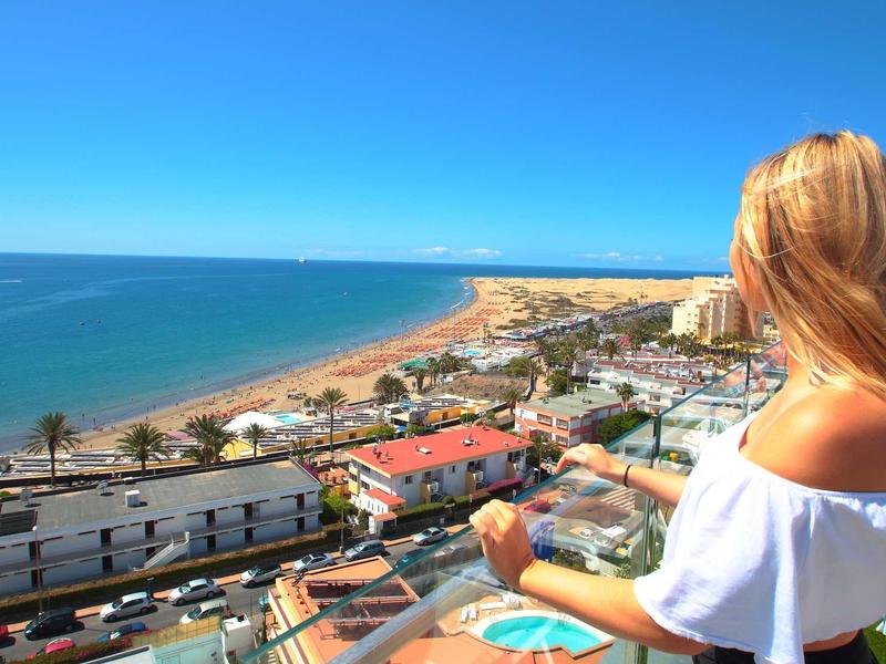 Kobieta patrzy na nadmorskie miasto z plażą i niebieskim morzem pod czystym niebem.