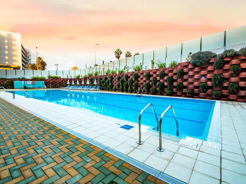 Nowoczesny obszar basenowy z czystą wodą, ogrodzeniem i niebem o zachodzie słońca.