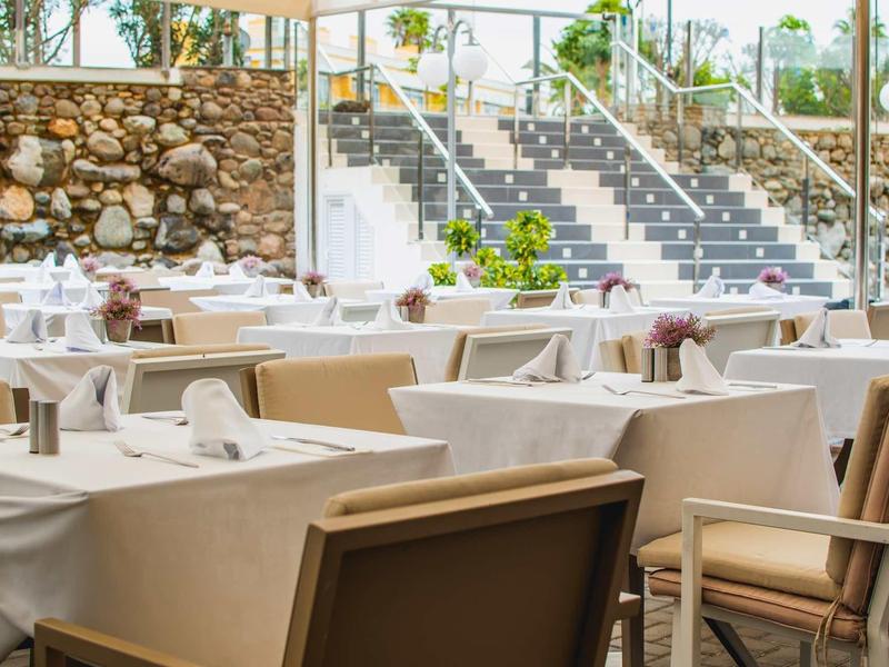 Elegancka restauracja z nakrytymi stołami i widokiem na zewnętrzny obszar ze schodami.