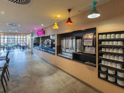Moderner Selbstbedienungsbereich mit Kaffeeautomaten, bunten Lampen und Sitzgelegenheiten.