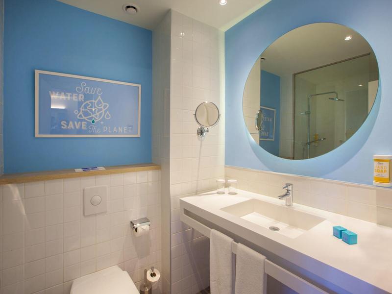 Modern bathroom with blue accent, large round mirror, and double sinks.