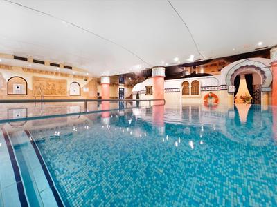 Ampia piscina coperta con acqua limpida e decorazioni calde beige.