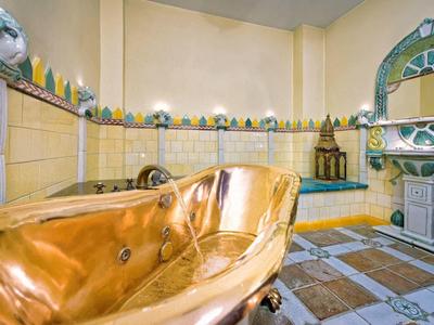 Vasca dorata con lavabo e decorazioni marocchine in un bagno lussuoso.