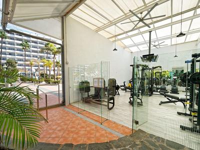 Modern gym with equipment behind glass partition and view of outdoor area.