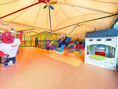 Area giochi coperta per bambini con scivoli colorati e giochi sotto un grande tendone.