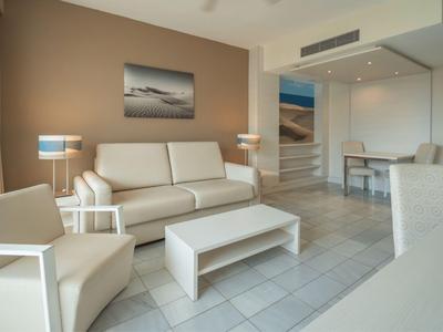 Modern eingerichtetes Wohnzimmer mit hellen Möbeln und Naturfotografie an der Wand.