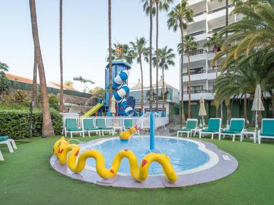Hotelpool mit Wasserrutschen, Sitzgelegenheiten und Palmen in tropischer Umgebung.