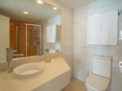 Hell ausgestattetes Badezimmer mit Waschbecken, Toilette und Duschkabine.