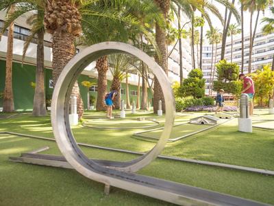 Moderner Minigolfplatz mit Palmen und großzügigem grünen Spielfeld im Freien.