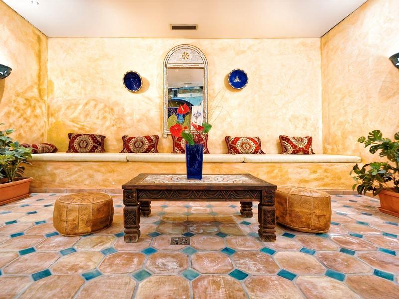 Salotto con pareti gialle, tavolino in legno basso e cuscini, stile marocchino.