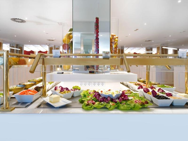 Buffet vario con frutta, verdure e piatti preparati in un ambiente pulito e luminoso.