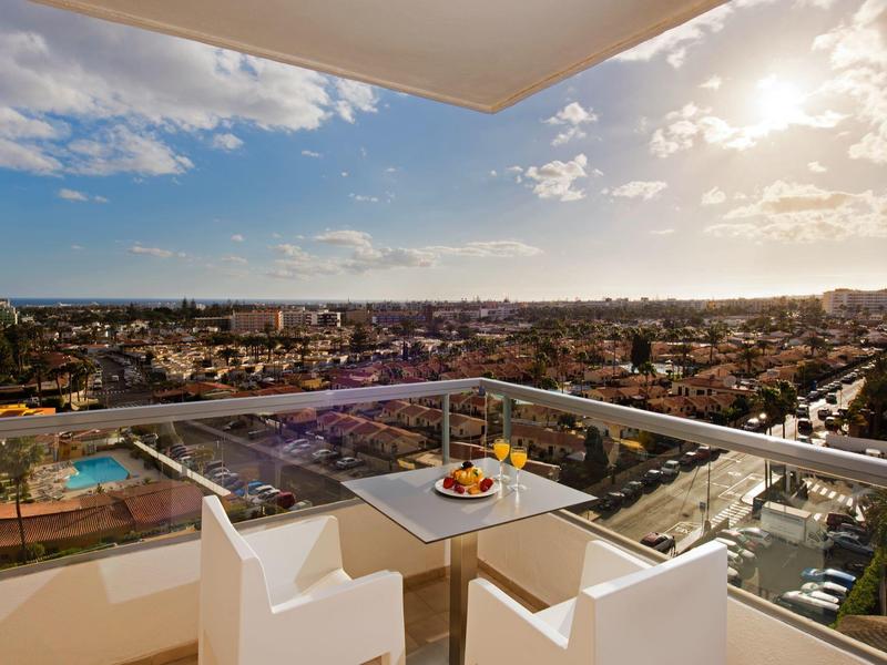 Balkon met stoelen en tafel met uitzicht op de stad en heldere lucht.