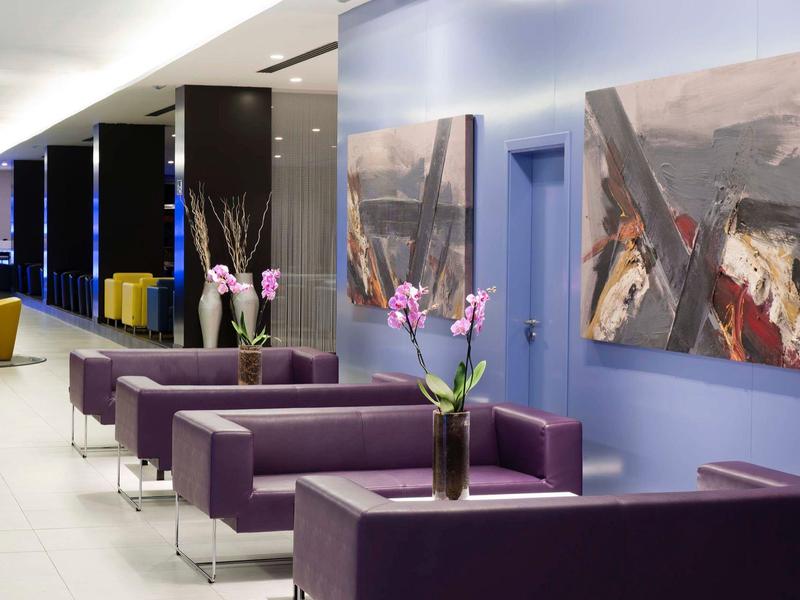 Moderne hotel lobby met paarse banken, kunst aan blauwe muren en verse bloemen in vazen.