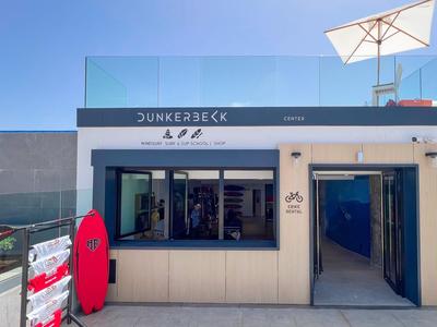 Bâtiment de plage moderne avec garde-corps en verre et parasol sous un ciel dégagé