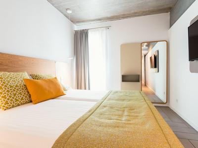 Przytulny pokój hotelowy z dużym łóżkiem, poduszkami i lustrem na ścianie.