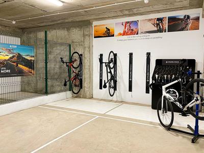 Espace de stationnement pour vélos avec plusieurs vélos suspendus dans un garage aux murs en béton.
