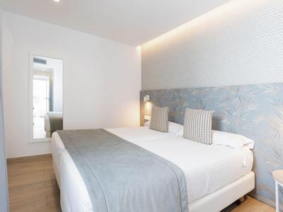 Nowoczesny pokój hotelowy z dużym łóżkiem, niebieskimi ścianami i minimalistycznym wystrojem.