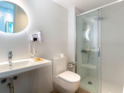 Nowoczesna łazienka z umywalką, toaletą, prysznicem i okrągłym lustrem.