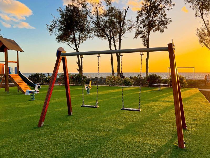 Plac zabaw z huśtawkami i drabinką o zachodzie słońca na zielonej trawie