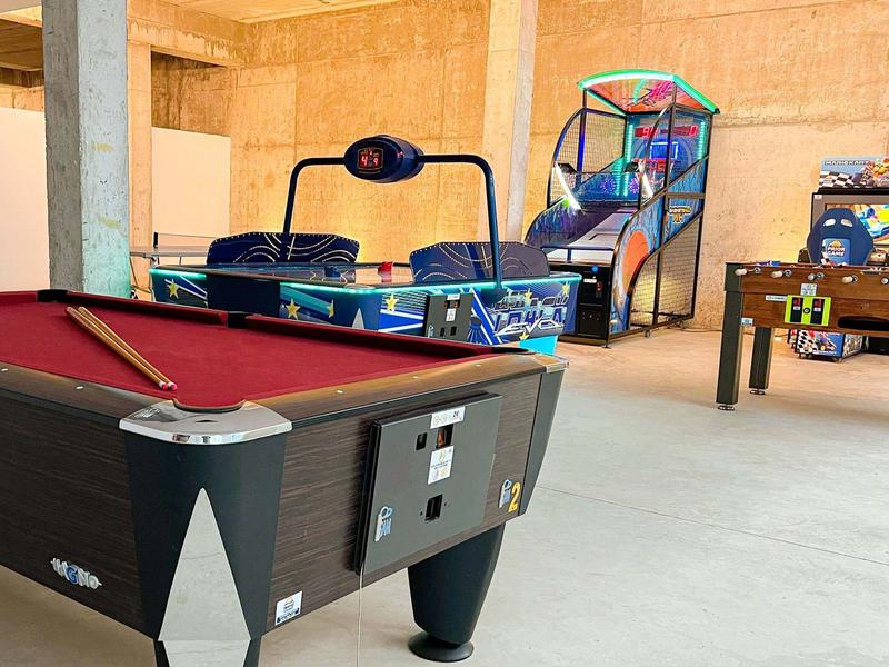 Strefa gier z bilardem, air hockey, piłkarzykami i automatami do gier w jasnym pomieszczeniu.