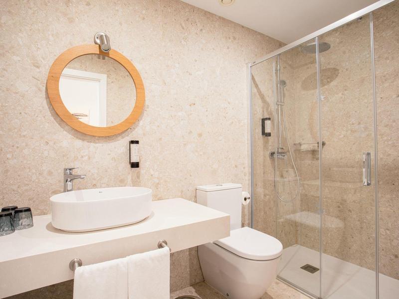 Nowoczesna łazienka z okrągłym lustrem, umywalką i szklaną prysznicem.